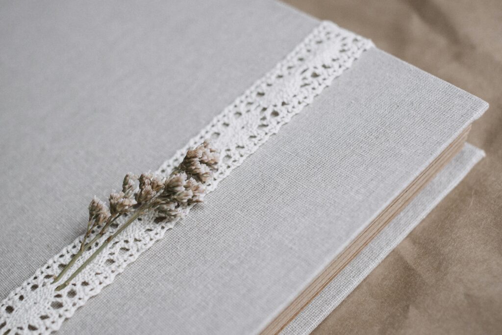 Linen-covered book with lace and dried flower detail, perfect for weddings or special occasions.